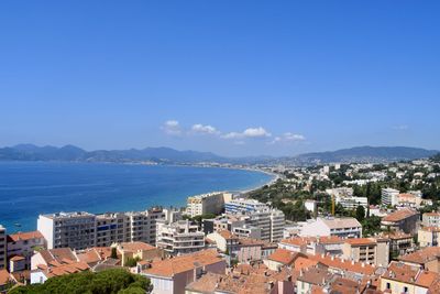 High angle view of townscape by sea against blue sky