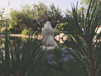 Sculpture by pond amidst trees in park