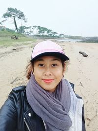 Portrait of smiling young woman on beach against sky