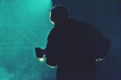 Rear view of silhouette man standing at music concert