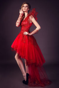 Portrait of young woman standing against red background