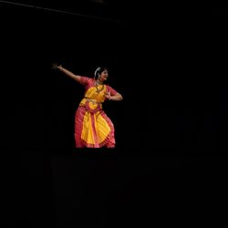 Midsection of woman dancing against black background