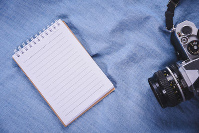 Close-up of camera and spiral notebook on table