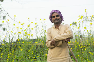 Happy farmer standing in field holding spade