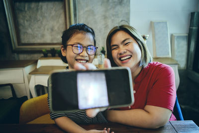 Asian mother and daughter showing smart phone screen and laughing with happiness face