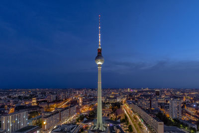 Illuminated buildings in city against blue sky