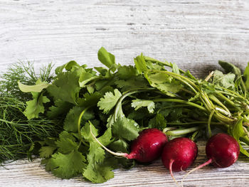 High angle view of radishes and herbs on wooden table