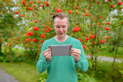 Young woman using mobile phone while standing on plants
