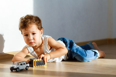 Portrait of cute boy with toy car on the floor