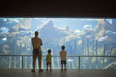 Rear view of people standing in aquarium