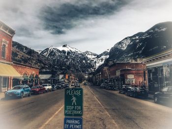 Vehicles on road by mountain against sky in city