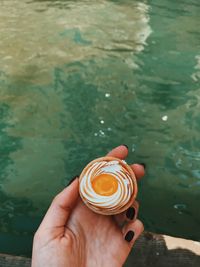 Cropped hand of woman holding sweet food over lake