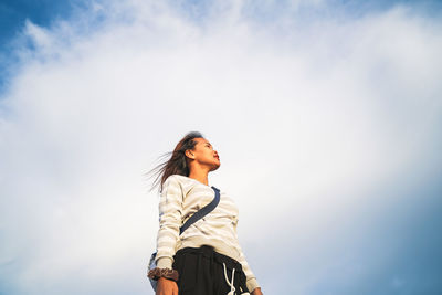 Low angle view of woman standing against sky