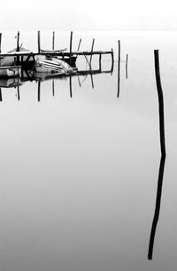 Wooden posts in lake against sky