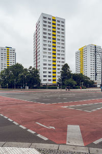 Road by buildings against sky in city