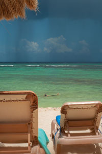 Chair on beach by sea against sky