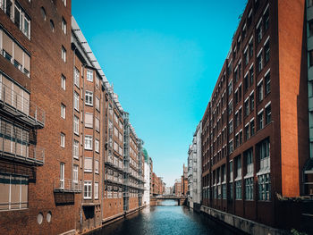 Canal amidst buildings against sky in city