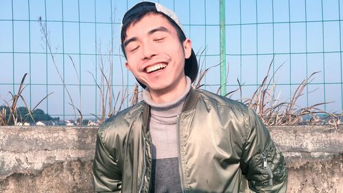 Portrait of smiling young man standing against sky