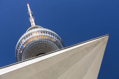 Low angle view of built structure by fernsehturm against clear blue sky