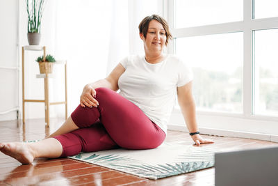 Young smiling woman practice yoga with laptop. physical and mental health