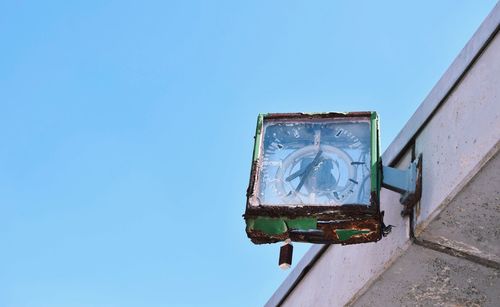 Low angle view of broken clock against clear blue sky