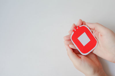 Cropped hand of person holding clock against white background