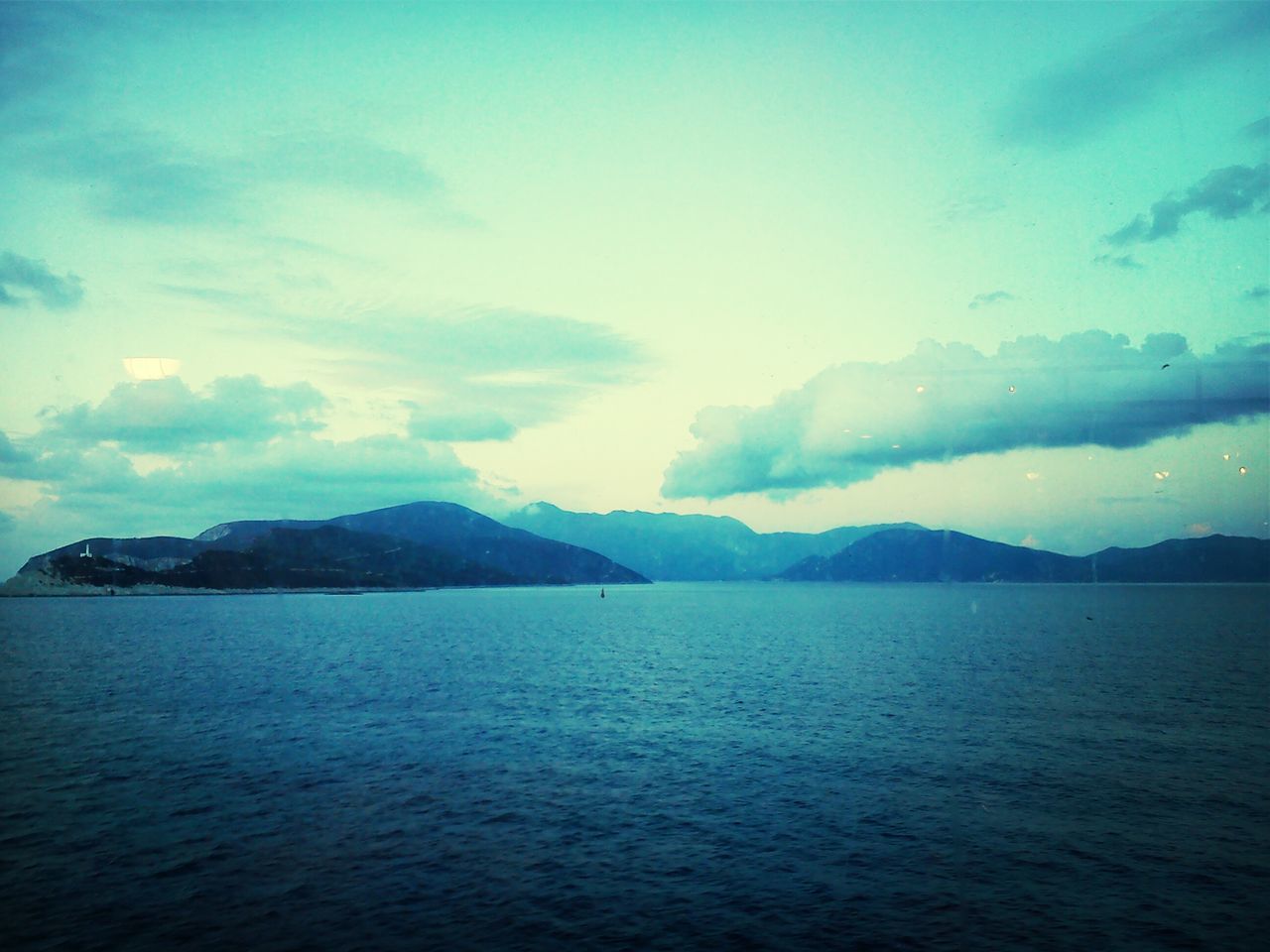 water, mountain, sea, scenics, tranquil scene, sky, tranquility, beauty in nature, waterfront, mountain range, cloud - sky, nature, cloud, idyllic, blue, cloudy, rippled, outdoors, dusk, no people