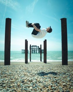 Man jumping on beach against sky