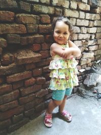 Portrait of smiling girl standing against brick wall