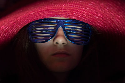 Close-up portrait of young woman wearing novelty glasses and red hat