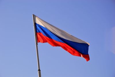 Low angle view of flag against clear blue sky