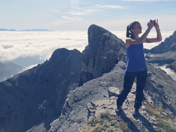 Full length of woman photographing on mountain against sky