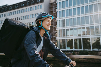 Smiling female biker wearing helmet and cycling in city