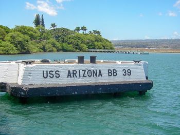 Close-up of information sign by sea against clear sky