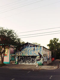 Graffiti on wall by road against sky