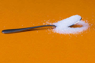 Close-up of fork on table against orange background