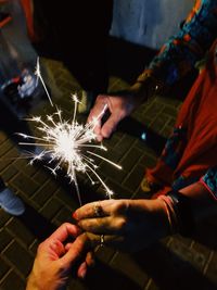 Cropped image of people holding illuminated sparkler at night