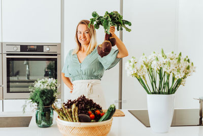 Woman holding beetroots while standing at the kitchen counter