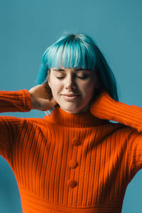 Young woman with eyes closed against blue background