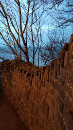 Stone wall on beach against sky at dusk