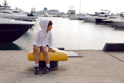 Boy child traveler sitting on the marina with yachts in sochi in the summer