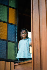 Low angle portrait of smiling girl seen through window