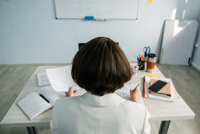 Young businesswoman, manager sitting at table in office and do notes in diary and calendar