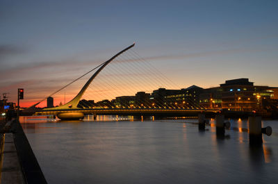 Silhouette bridge over river against sky at sunset