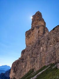 Low angle view of rocky mountain against blue sky