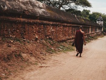 Rear view of woman walking on street amidst trees