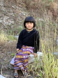 Portrait of young woman sitting on field