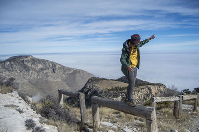 Woman standing on mountain against sky