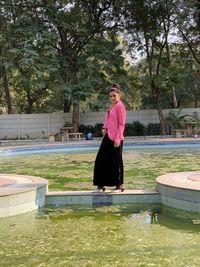 Woman standing by swimming pool against lake