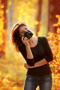 Full length of young woman photographing during autumn